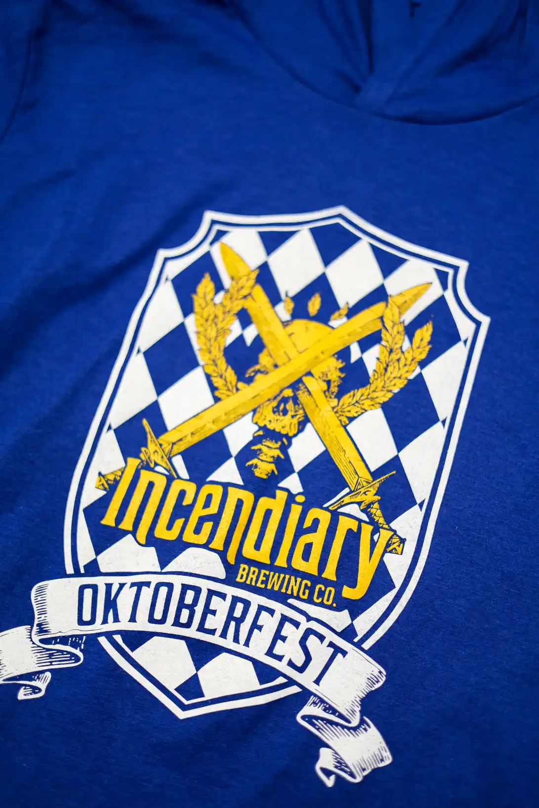 Royal blue hooded long sleeve shirt with the full color Oktoberfest crest printed on the front