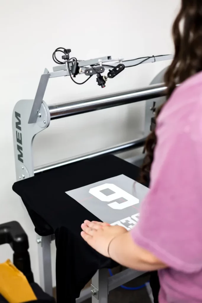 Overhead view of an employee aligning a number transfer on a heat press machine