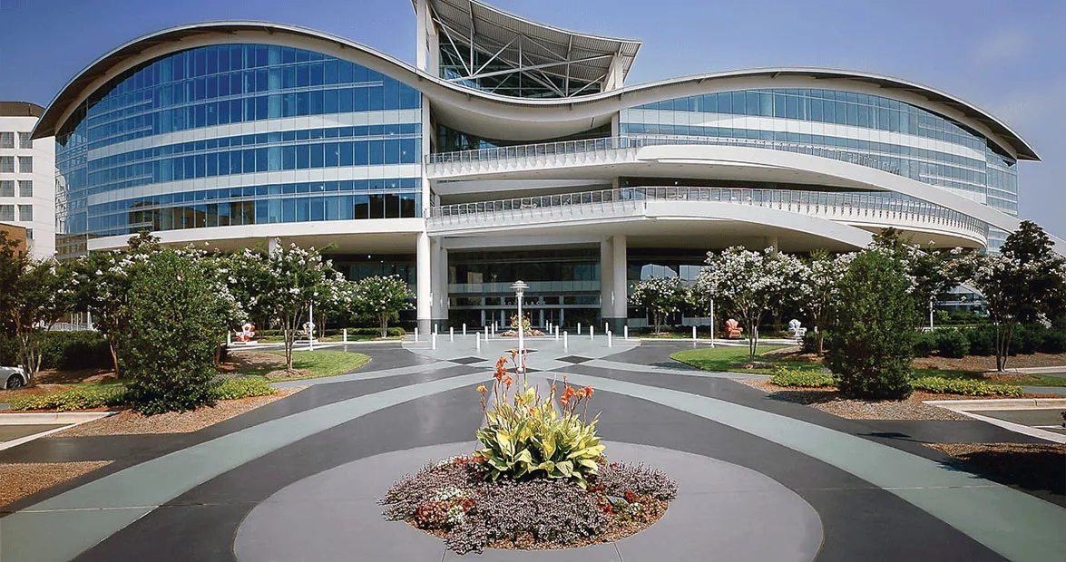 Modern curved glass building with a landscaped entrance plaza